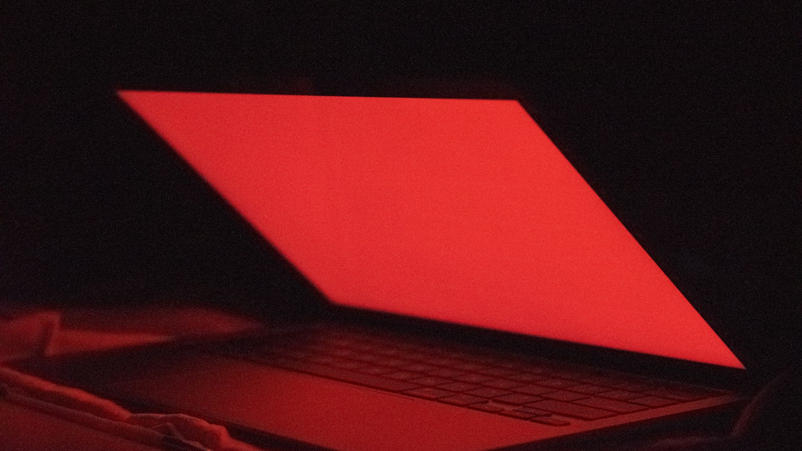 A laptop screen lit up in a dark room